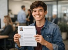 Adolescente sorridente segura um currículo em destaque, com um escritório moderno desfocado ao fundo. A cena transmite confiança, expectativa e o início da vida profissional, com iluminação suave e enquadramento natural.
